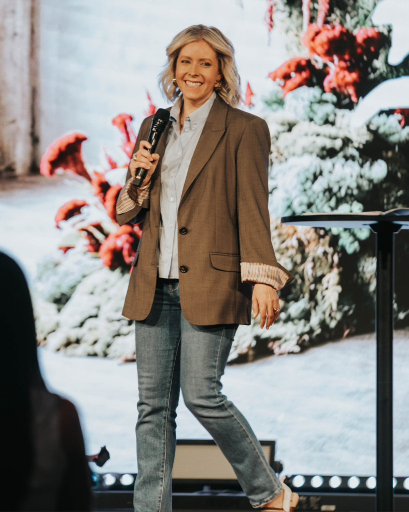 Carrie Pasch speaking on stage with a microphone